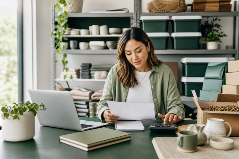 Small retail seller reconciling marketplace payouts, inventory records, and business bank deposits at a desk